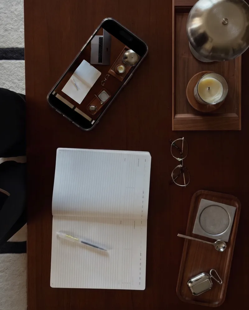 Top-down creative planning desk with a phone, notebook and glasses